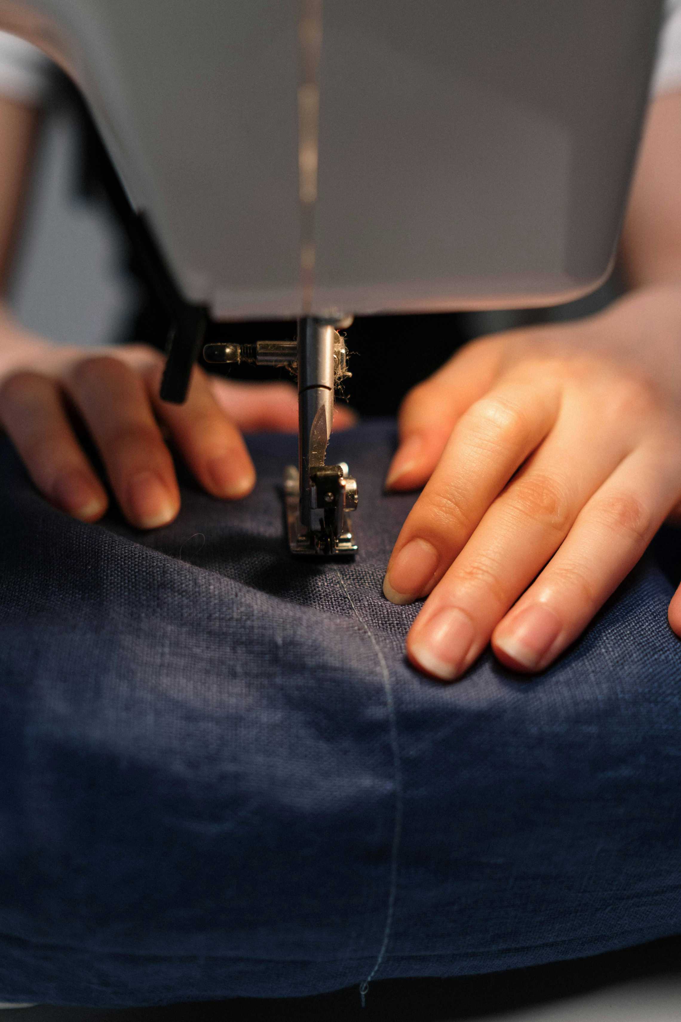 Mãos costurando em uma máquina de costura